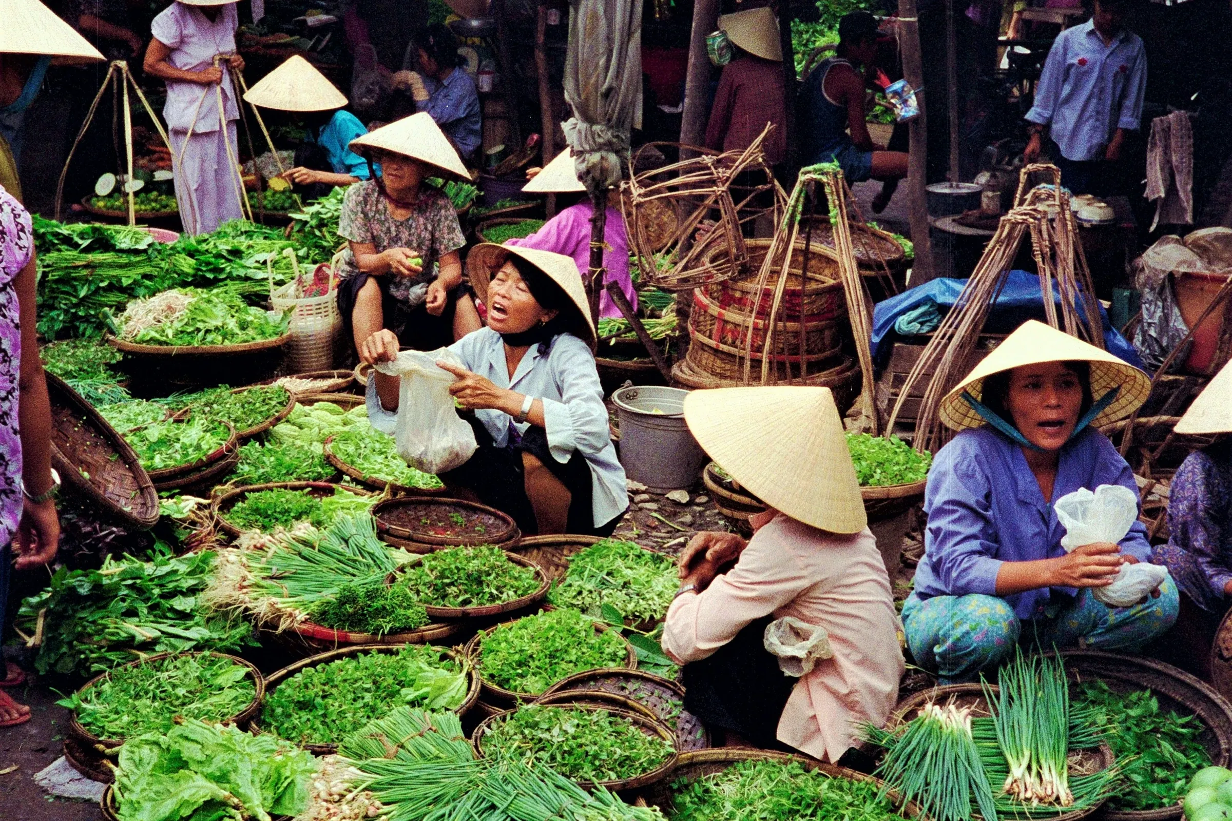 Grøntsager og handlende på et marked i Hoi An
