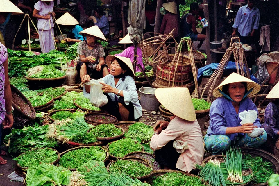 Grøntsager og handlende på et marked i Hoi An