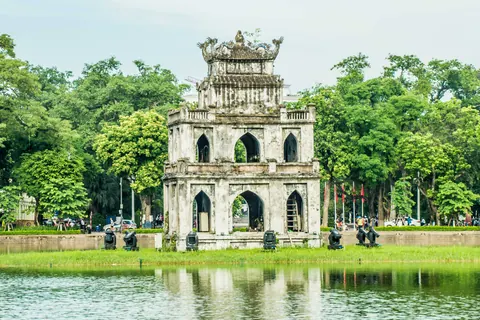 Historisk bygning ved vandet og træerne i Hanoi