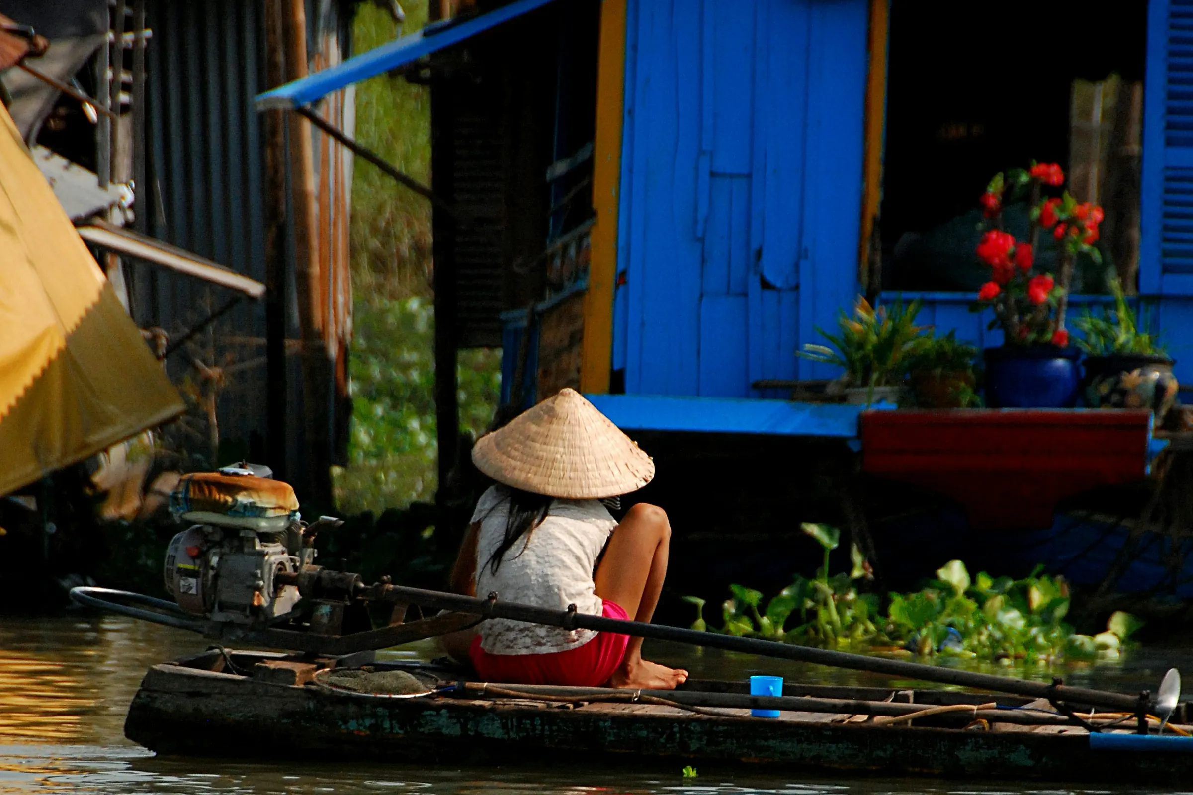 En person med keglehat i en båd ved Chau Doc