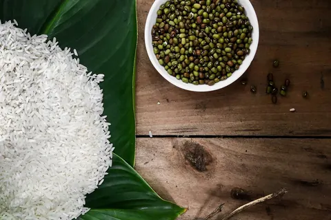 Hvide ris på et grønt blad ved siden af en skål grønne bønner, fotograferet i Ho Chi Minh-byen