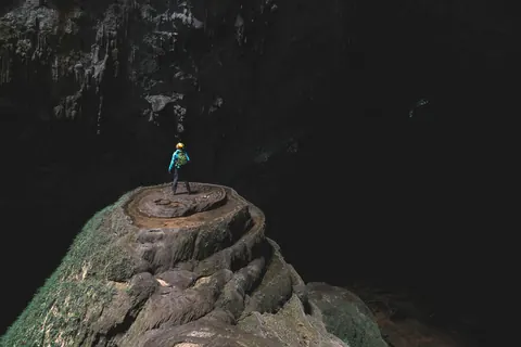 En person på en klippeformation inde i Son Doong-grotten